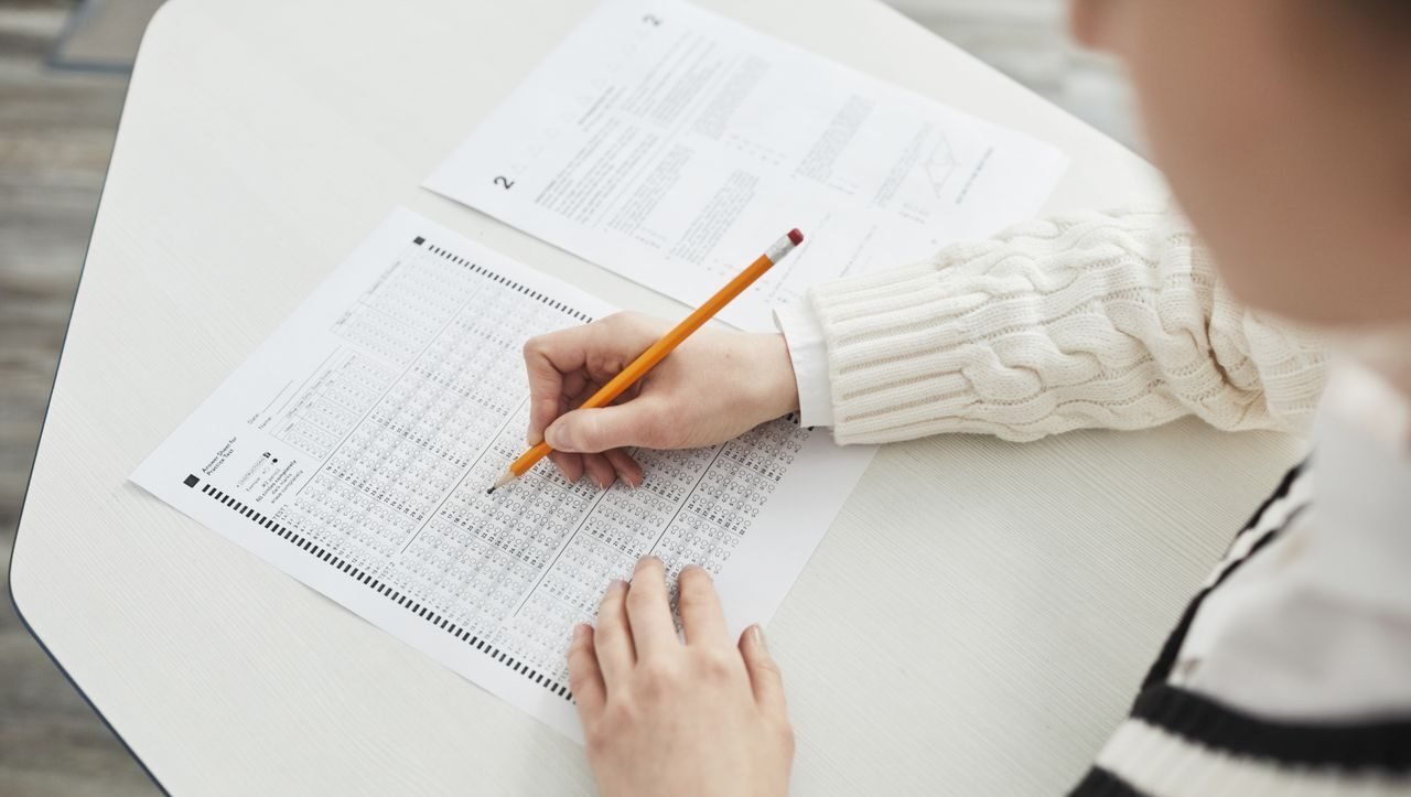 Close-up of a student filling out a multiple-choice exam in a quiet classroom setting.