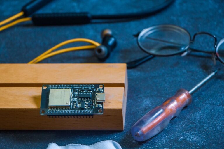 Close-up of an Arduino circuit board on a workshop table with tools and gadgets, showcasing DIY electronics.